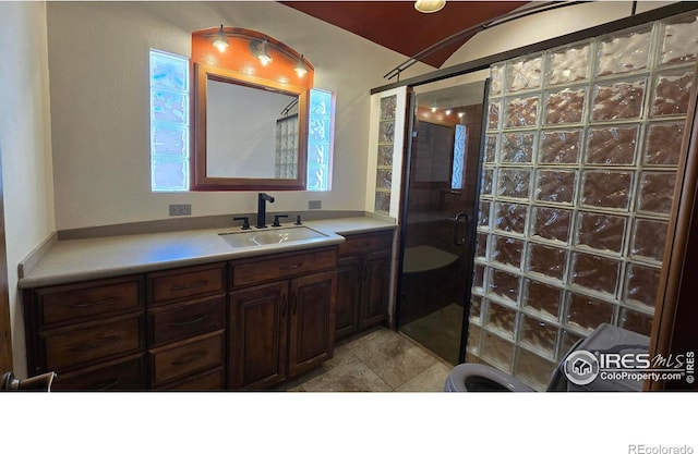 bathroom featuring tile patterned flooring, a shower with shower door, and vanity