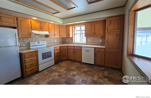 kitchen featuring white appliances, backsplash, and sink