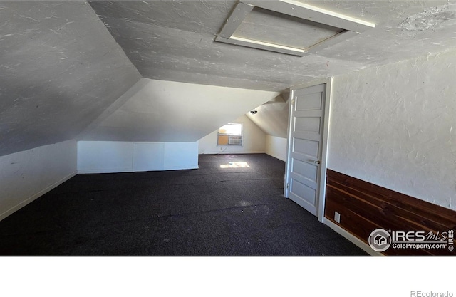 bonus room featuring a textured ceiling, carpet floors, and vaulted ceiling