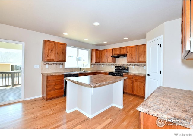 708 85th Avenue Ct, Greeley, CO 80634 - kitchen with black range with electric stovetop, under cabinet range hood, light wood-type flooring, brown cabinetry, and a sink