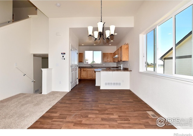 kitchen with a wealth of natural light, dark hardwood / wood-style flooring, pendant lighting, and an inviting chandelier