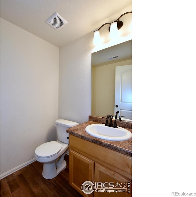 bathroom with hardwood / wood-style floors, vanity, and toilet