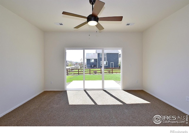 empty room featuring carpet floors, baseboards, visible vents, and ceiling fan