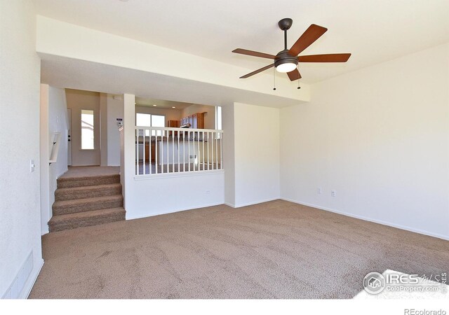 spare room featuring stairs, ceiling fan, carpet, and baseboards