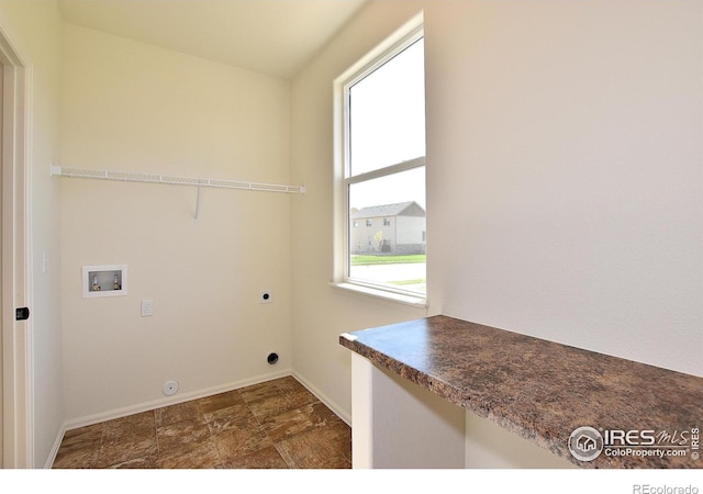 laundry area with laundry area, baseboards, stone finish floor, hookup for an electric dryer, and washer hookup