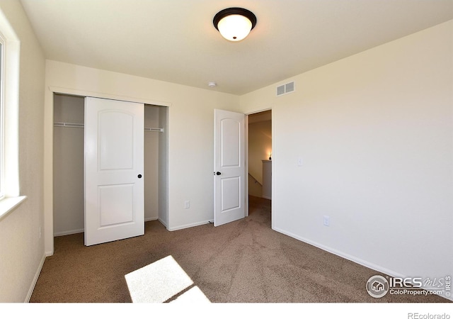 unfurnished bedroom featuring carpet floors, a closet, visible vents, and baseboards