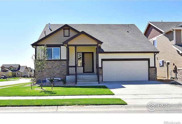 craftsman-style home featuring driveway, a garage, a shingled roof, stone siding, and a front yard