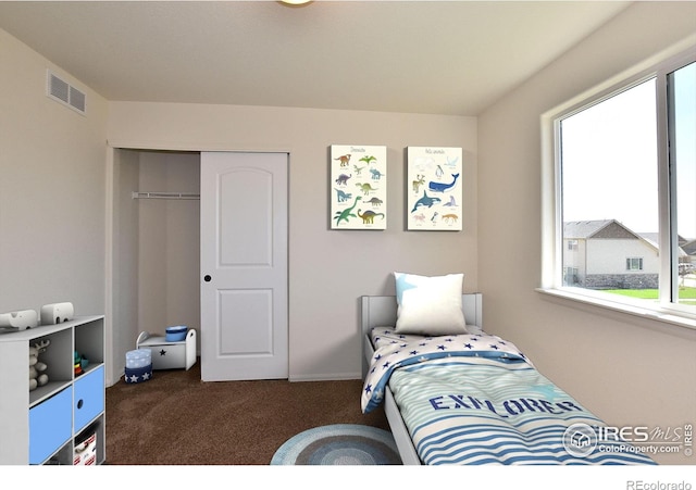 bedroom with visible vents, dark colored carpet, and a closet