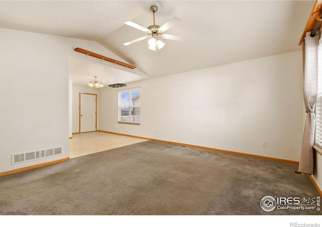 carpeted spare room with ceiling fan with notable chandelier and vaulted ceiling