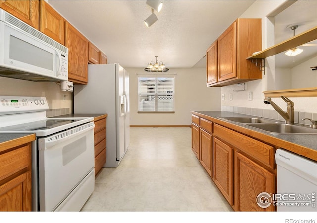 kitchen with white appliances, a chandelier, sink, and a textured ceiling