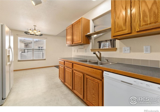 kitchen with sink, white appliances, an inviting chandelier, and a textured ceiling