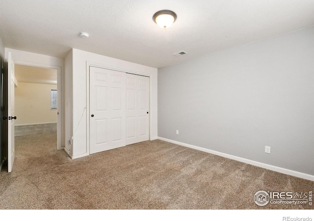 unfurnished bedroom featuring carpet flooring, a textured ceiling, and a closet