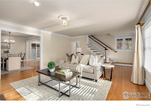 living room with crown molding, light hardwood / wood-style flooring, and a notable chandelier