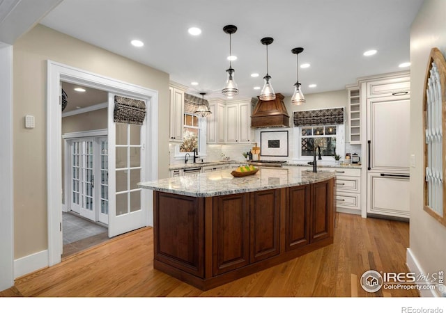 kitchen featuring backsplash, light hardwood / wood-style flooring, a kitchen island, and pendant lighting