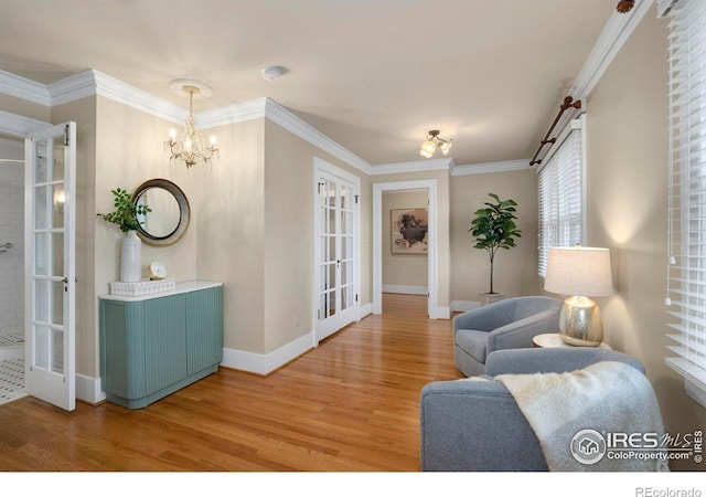 living room with wood-type flooring, an inviting chandelier, french doors, and crown molding