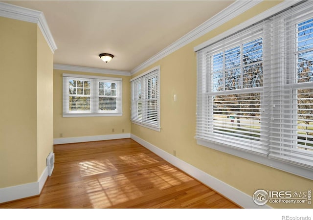 unfurnished room featuring ornamental molding, a healthy amount of sunlight, and hardwood / wood-style flooring