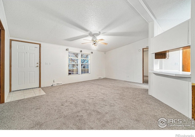 unfurnished living room featuring light carpet, ceiling fan, and a textured ceiling