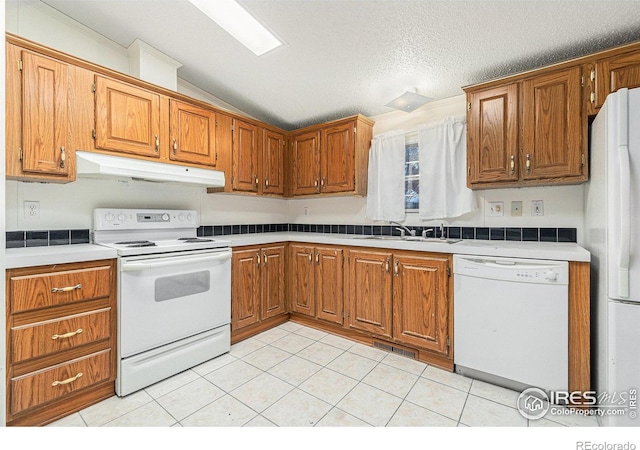 kitchen featuring light tile patterned flooring, white appliances, lofted ceiling, and sink