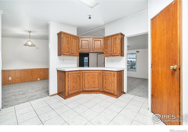 kitchen featuring decorative light fixtures, wood walls, light tile patterned flooring, and a textured ceiling