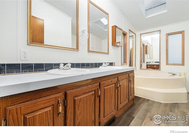 bathroom featuring hardwood / wood-style flooring, a washtub, a textured ceiling, and vanity