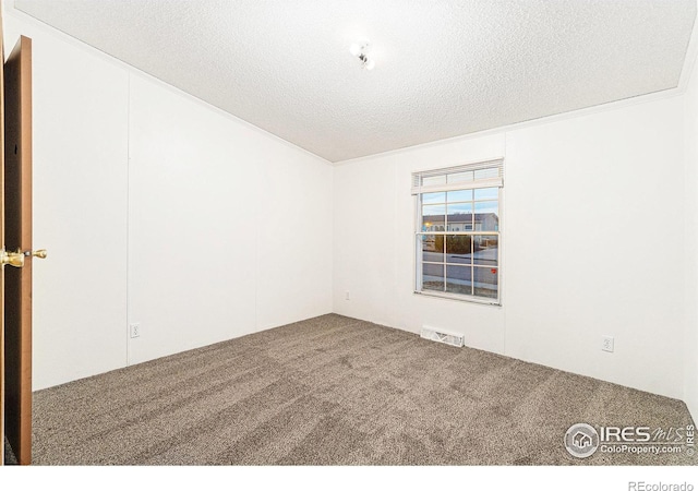 carpeted empty room featuring a textured ceiling