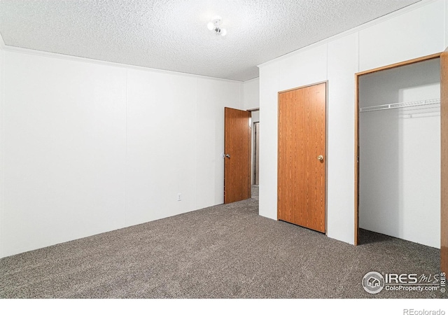 unfurnished bedroom featuring multiple closets, dark carpet, and a textured ceiling