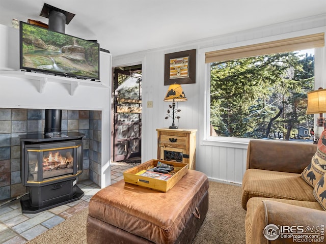 living room with light colored carpet, a wood stove, and a wealth of natural light