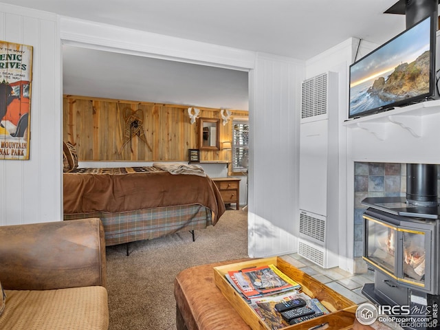 carpeted bedroom featuring a wood stove and wooden walls