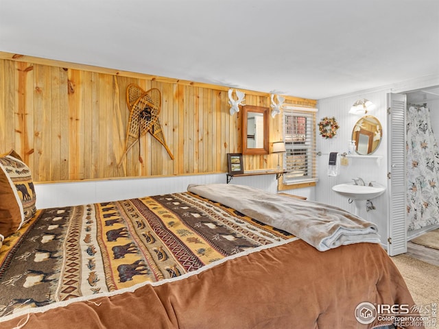 unfurnished bedroom with ensuite bathroom, carpet floors, and wooden walls