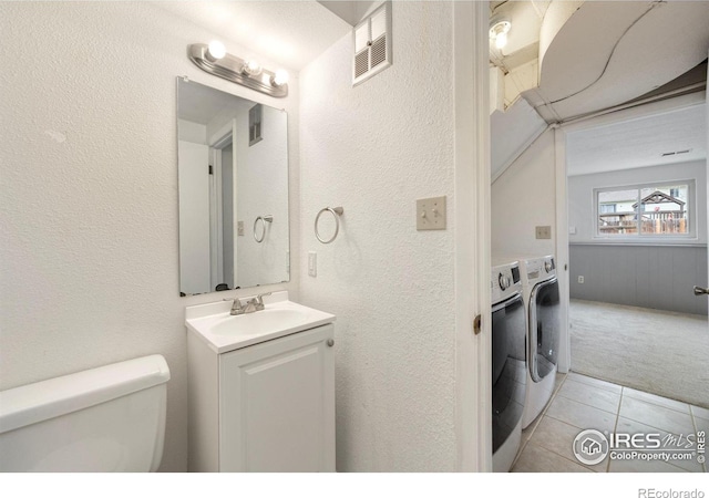 bathroom featuring vanity, washing machine and clothes dryer, tile patterned floors, and toilet