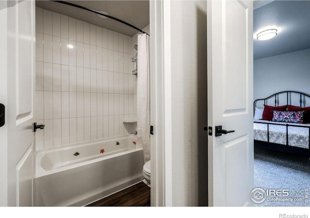 bathroom featuring hardwood / wood-style floors, tiled shower / bath combo, and toilet