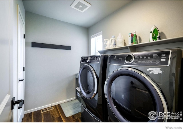 clothes washing area with separate washer and dryer and dark wood-type flooring