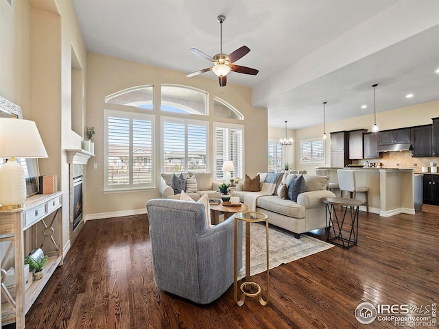 living room with ceiling fan with notable chandelier, dark hardwood / wood-style flooring, and lofted ceiling