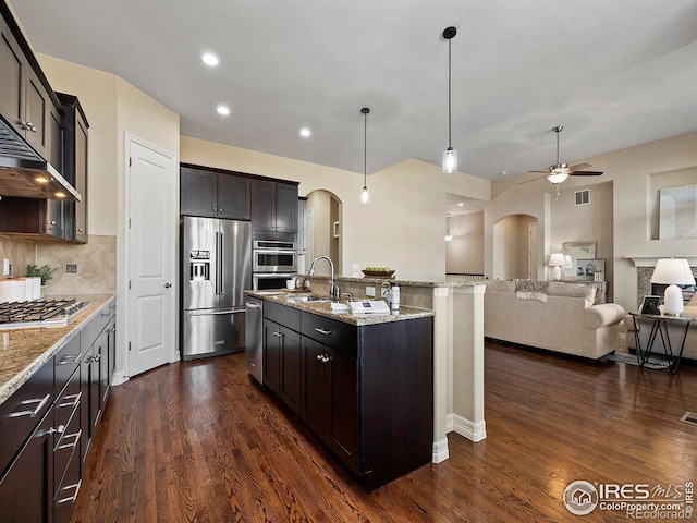 kitchen with dark hardwood / wood-style floors, hanging light fixtures, a kitchen island with sink, and appliances with stainless steel finishes