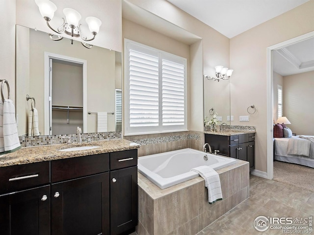 bathroom featuring tile patterned floors, vanity, a relaxing tiled tub, and an inviting chandelier