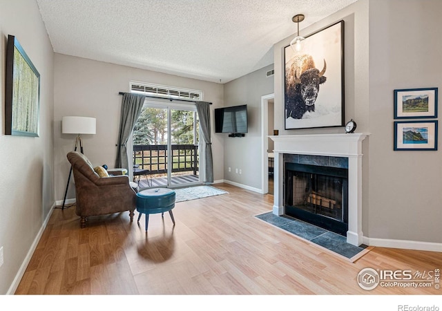 living area with hardwood / wood-style flooring, a textured ceiling, and a tiled fireplace