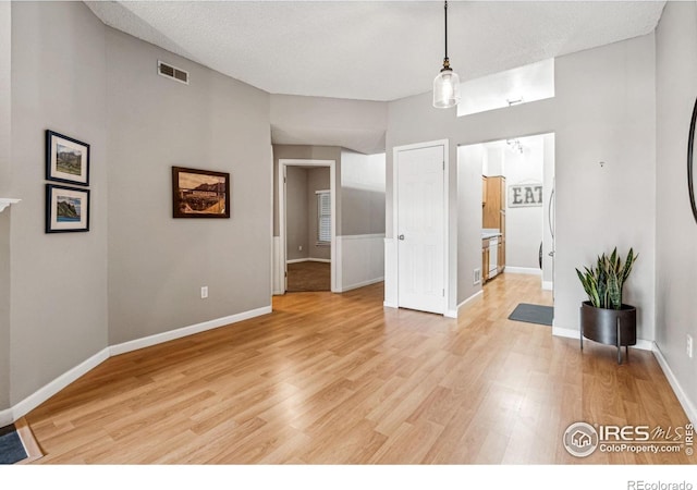 unfurnished dining area with a textured ceiling and light wood-type flooring