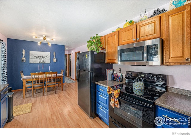 kitchen with light hardwood / wood-style flooring, black appliances, and a textured ceiling