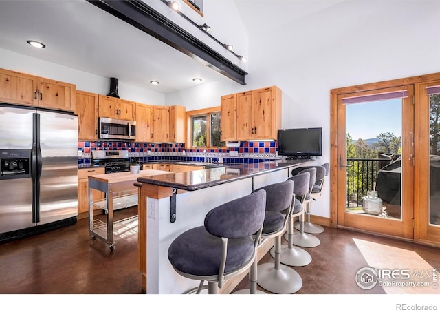 kitchen with backsplash, kitchen peninsula, a kitchen breakfast bar, and appliances with stainless steel finishes