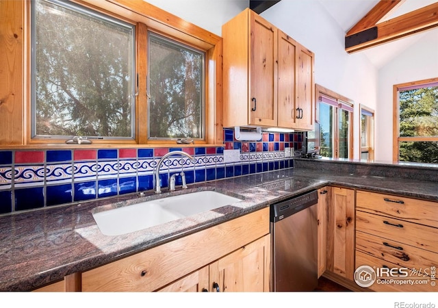 kitchen with stainless steel dishwasher, dark stone countertops, lofted ceiling, and sink