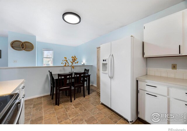 kitchen with white cabinets, white fridge with ice dispenser, and stainless steel electric stove