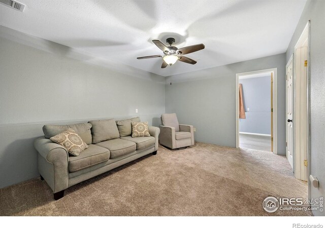 carpeted living room featuring ceiling fan and a textured ceiling