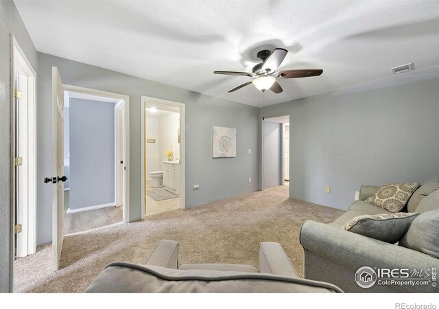 carpeted living room featuring ceiling fan and a textured ceiling