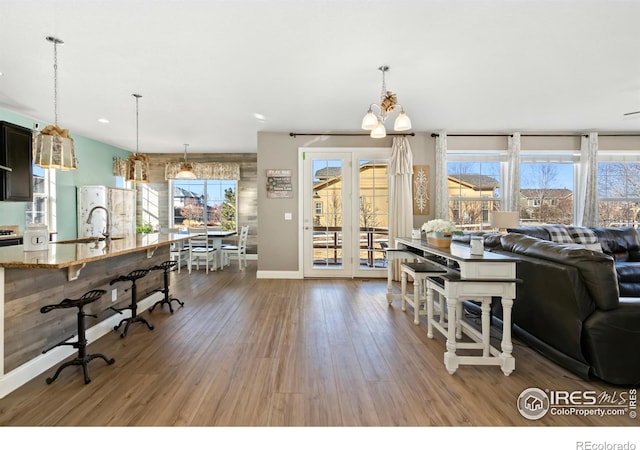 living room featuring sink, a notable chandelier, dark hardwood / wood-style floors, and a healthy amount of sunlight