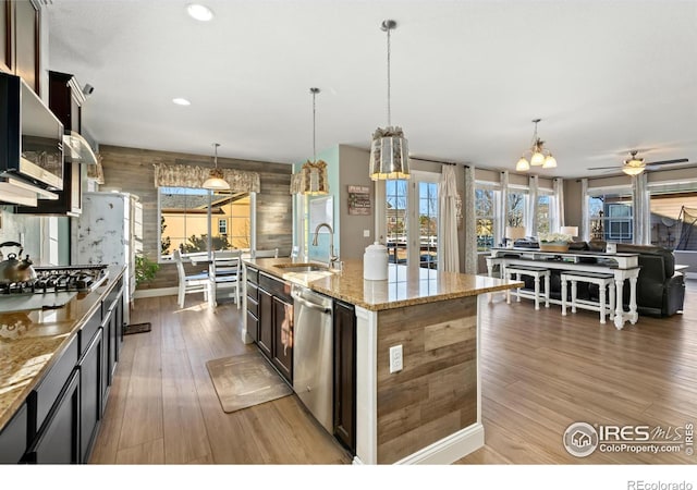 kitchen featuring pendant lighting, sink, a center island with sink, and light stone counters