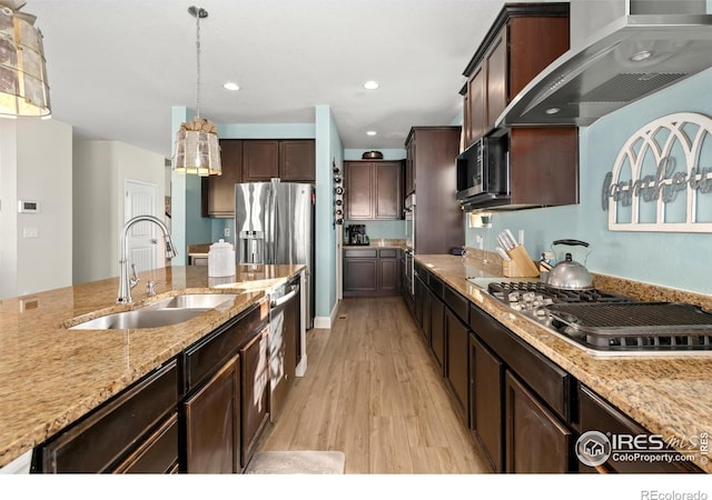 kitchen with appliances with stainless steel finishes, decorative light fixtures, sink, dark brown cabinets, and wall chimney exhaust hood