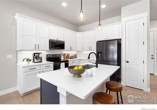 kitchen with a kitchen island with sink, sink, stainless steel appliances, and decorative light fixtures