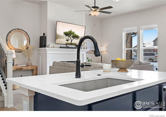 kitchen featuring blue cabinetry, carpet, ceiling fan, and sink