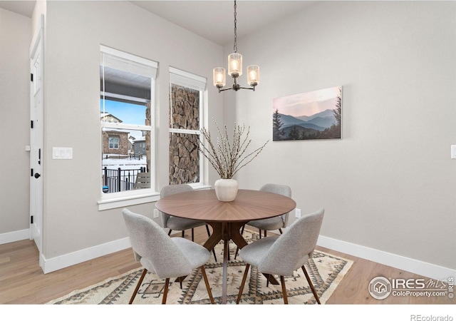 dining area with light hardwood / wood-style flooring and a notable chandelier