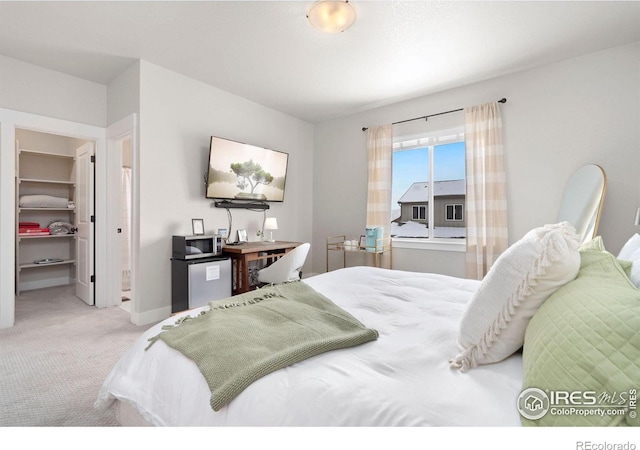 carpeted bedroom with a walk in closet and a closet